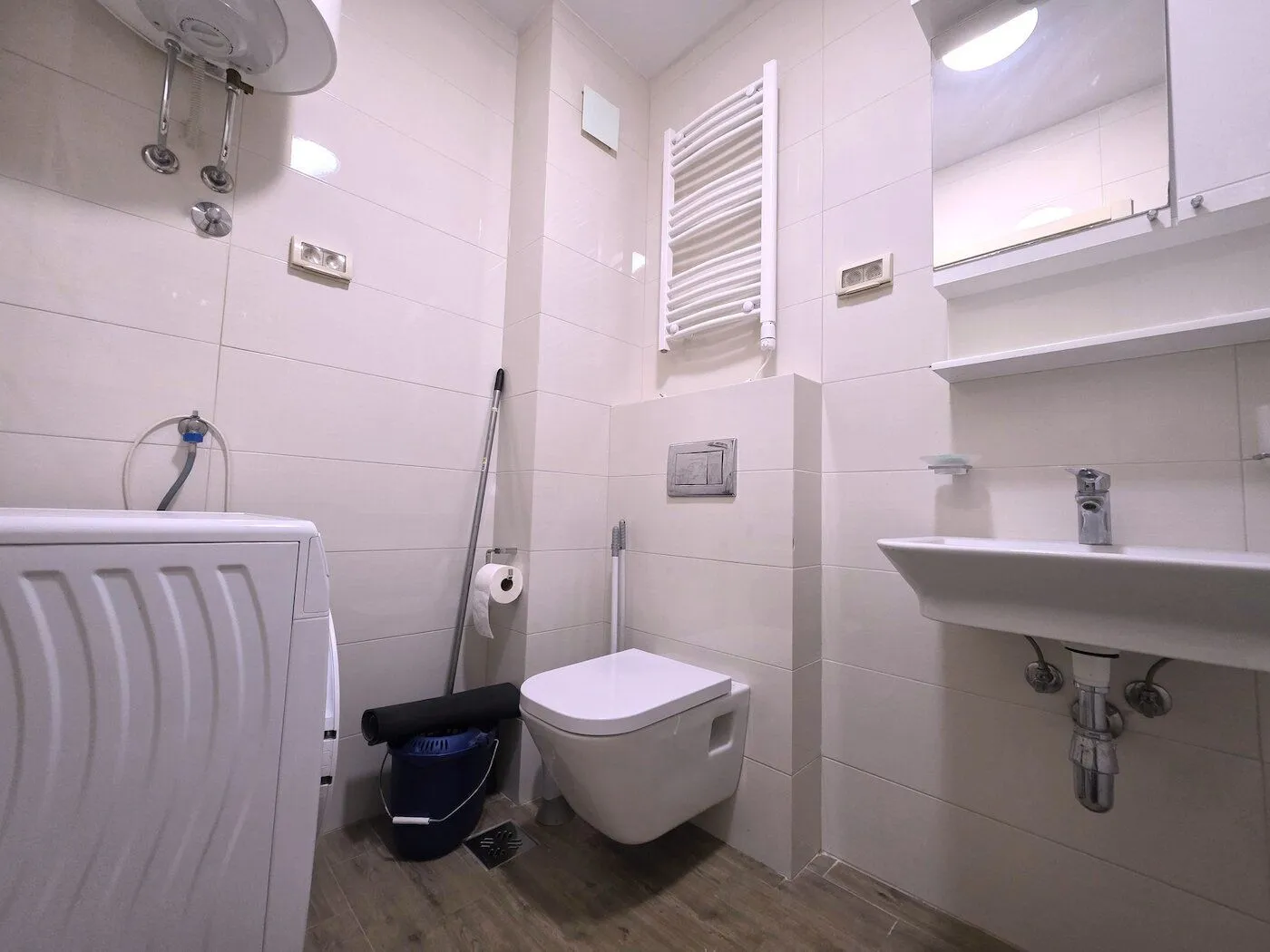 Bathroom equipped with a toilet, sink, water heater, and washing machine.