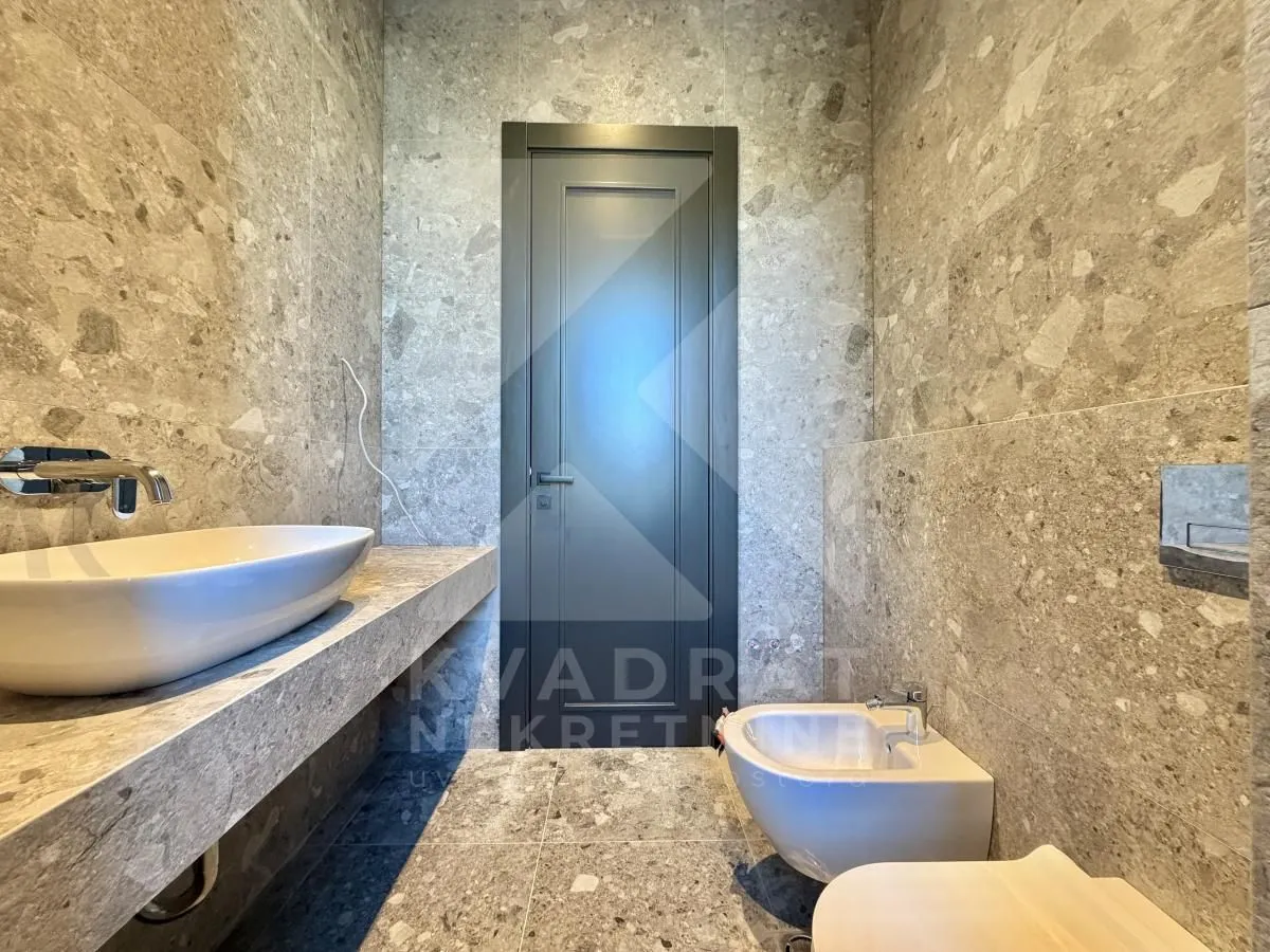 Modern bathroom equipped with grey ceramic tiles and a washbasin.