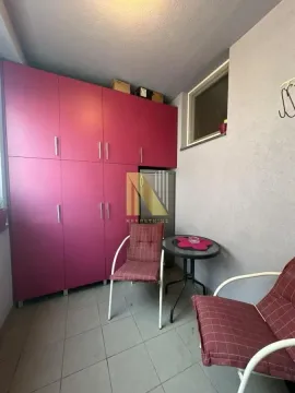 Zastakljeni balkon sa roze ormarom i stolom za sedenje. - image 15