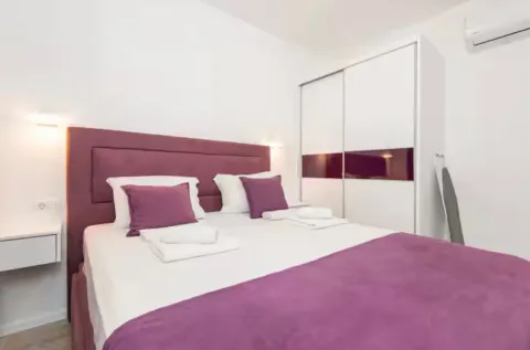 Bright bedroom with a double bed, white wardrobe, and air conditioning. - image 9