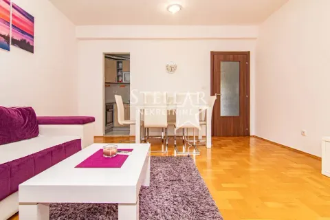 Living room with a sofa, coffee table, and a dining area in the background. - image 3