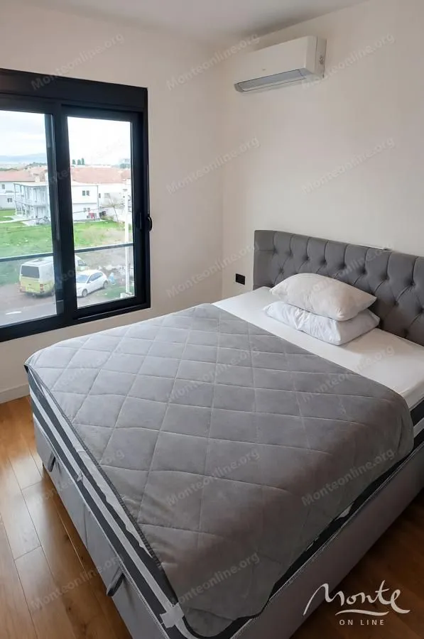 Bedroom with a double bed, air conditioning unit, and a window overlooking the neighborhood.