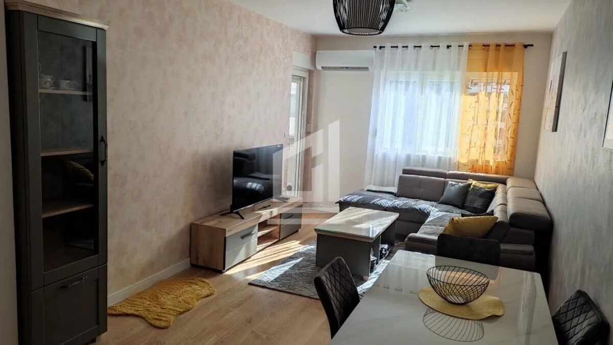 Living room with a sofa, TV unit, and dining table.