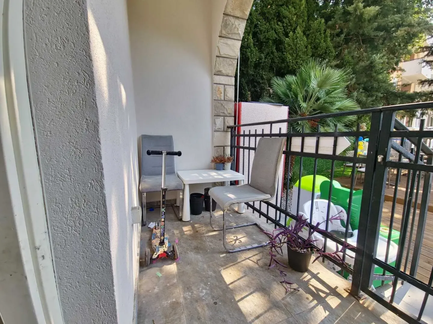 Covered balcony with a table, chairs, and metal railing.