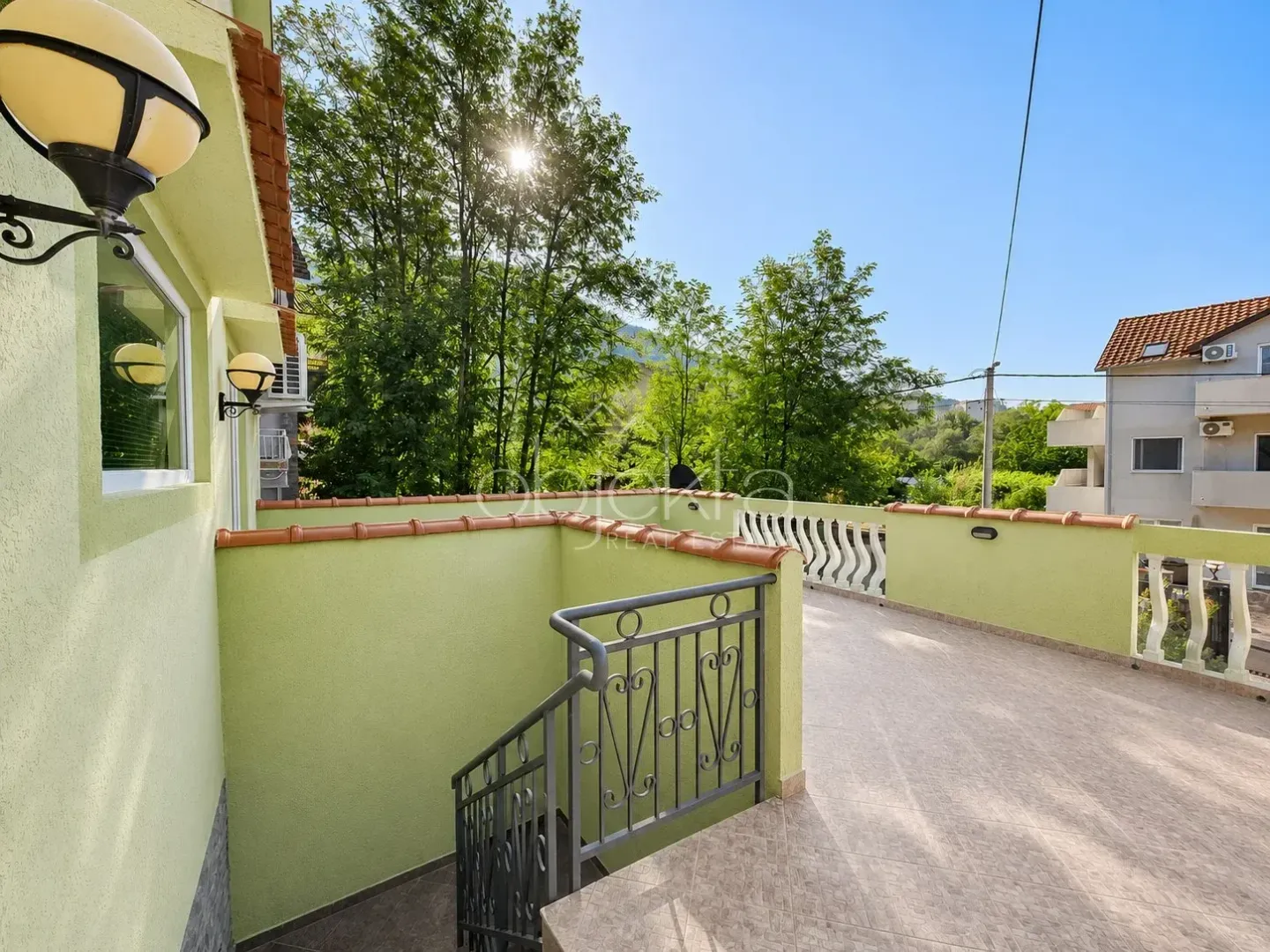 Velika popločana terasa sa stepeništem i pogledom na zelenilo.
