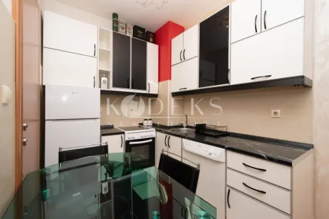 Smaller kitchen with white and dark cabinets and a dining table in the foreground. - image 2