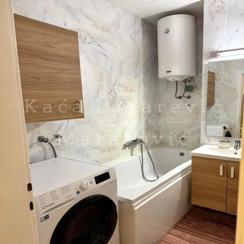 Bathroom equipped with a bathtub, washbasin, water heater, and washing machine.