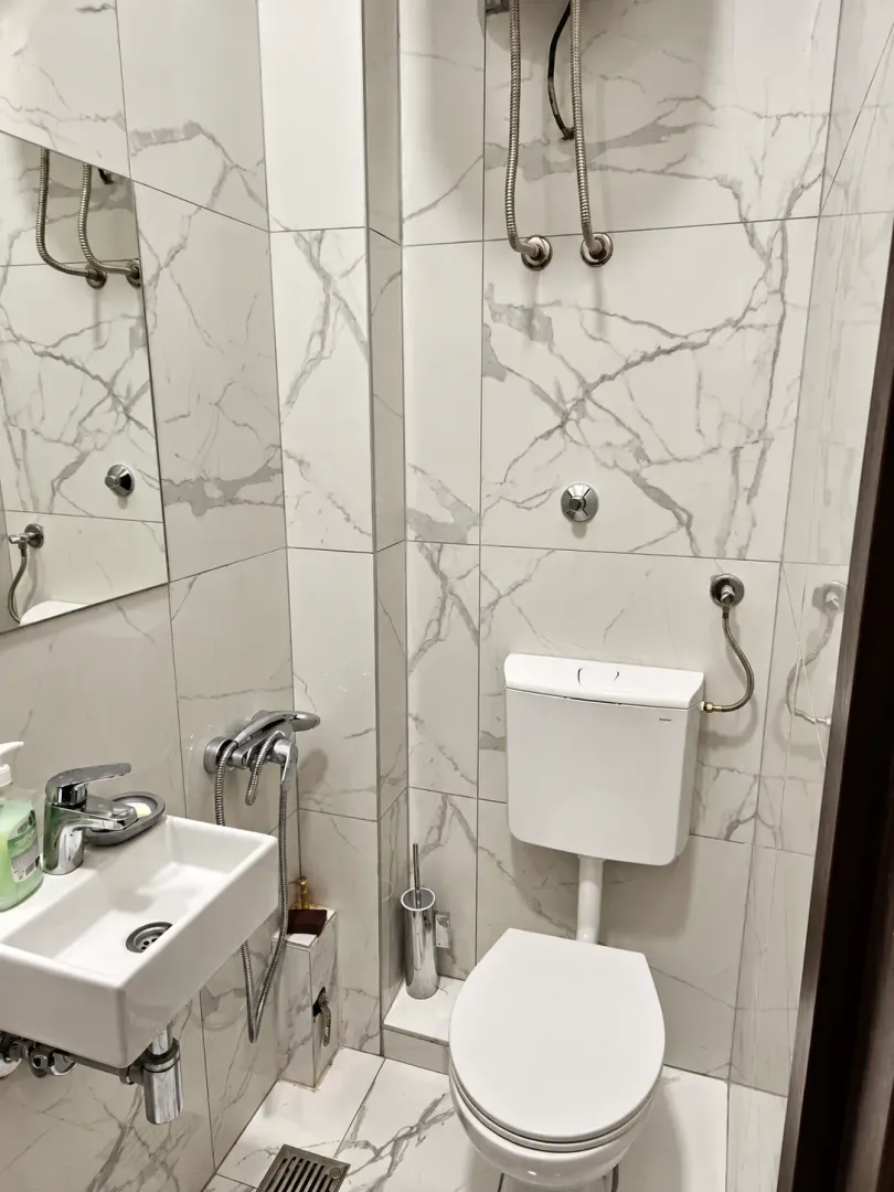 Modernly equipped bathroom with marble tiles, washbasin, and toilet.