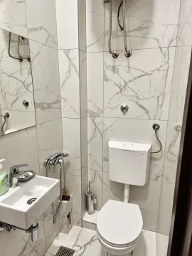 Modernly equipped bathroom with marble tiles, washbasin, and toilet. - image 6