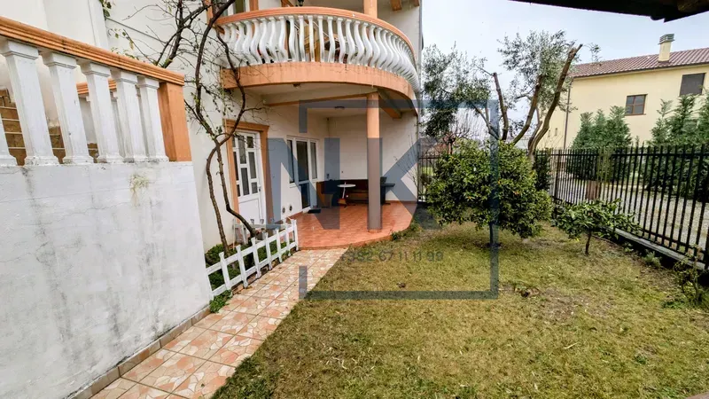 Yard of the house with a tiled path, lawn, and terrace.
