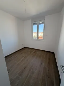 Prazna soba sa belim zidovima, drvenim podom i prozorom. - image 9