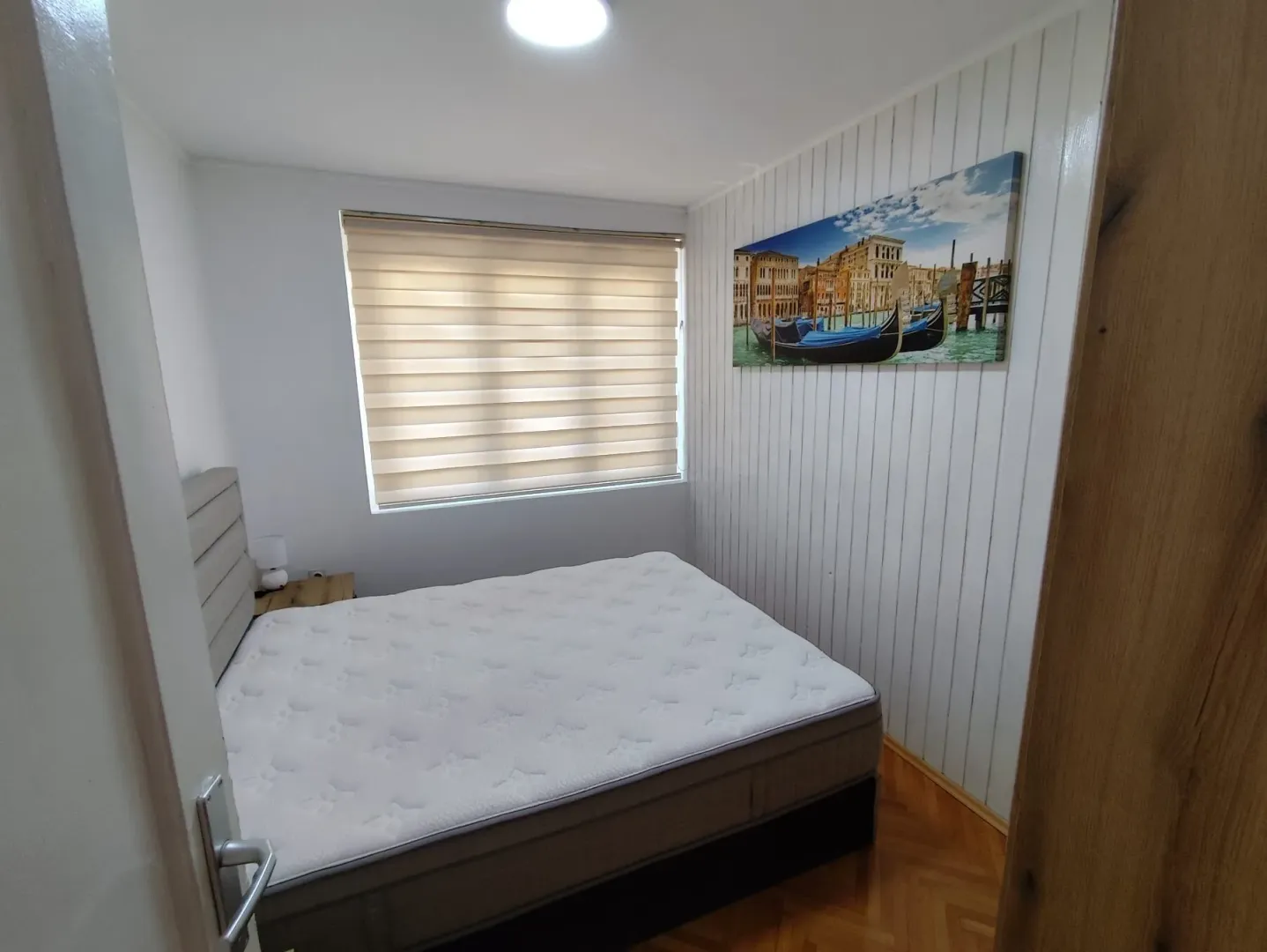Manja spavaća soba sa bračnim krevetom i prozorom.