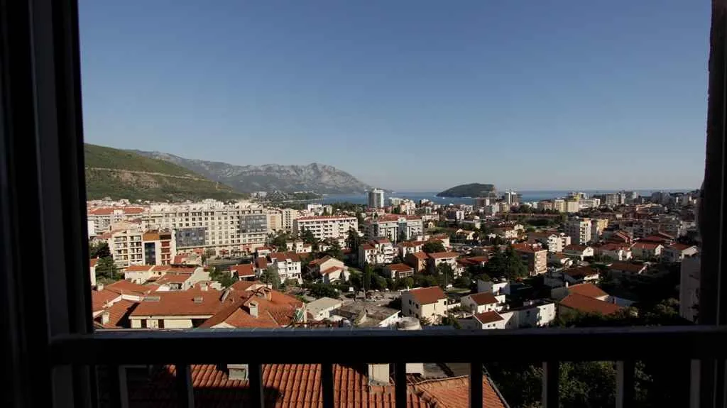 Pogled sa balkona na grad i more u daljini.