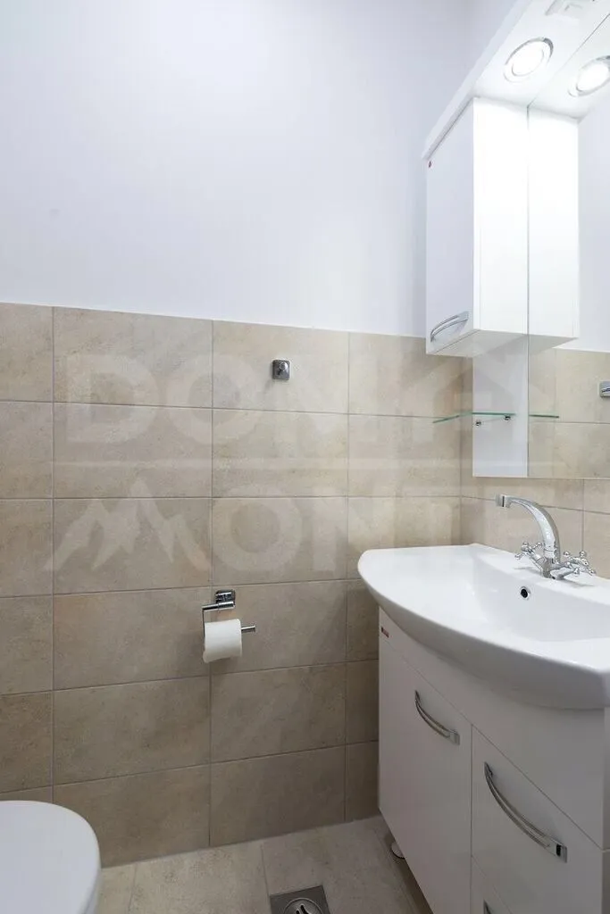 Small bathroom with a washbasin and white vanity units.
