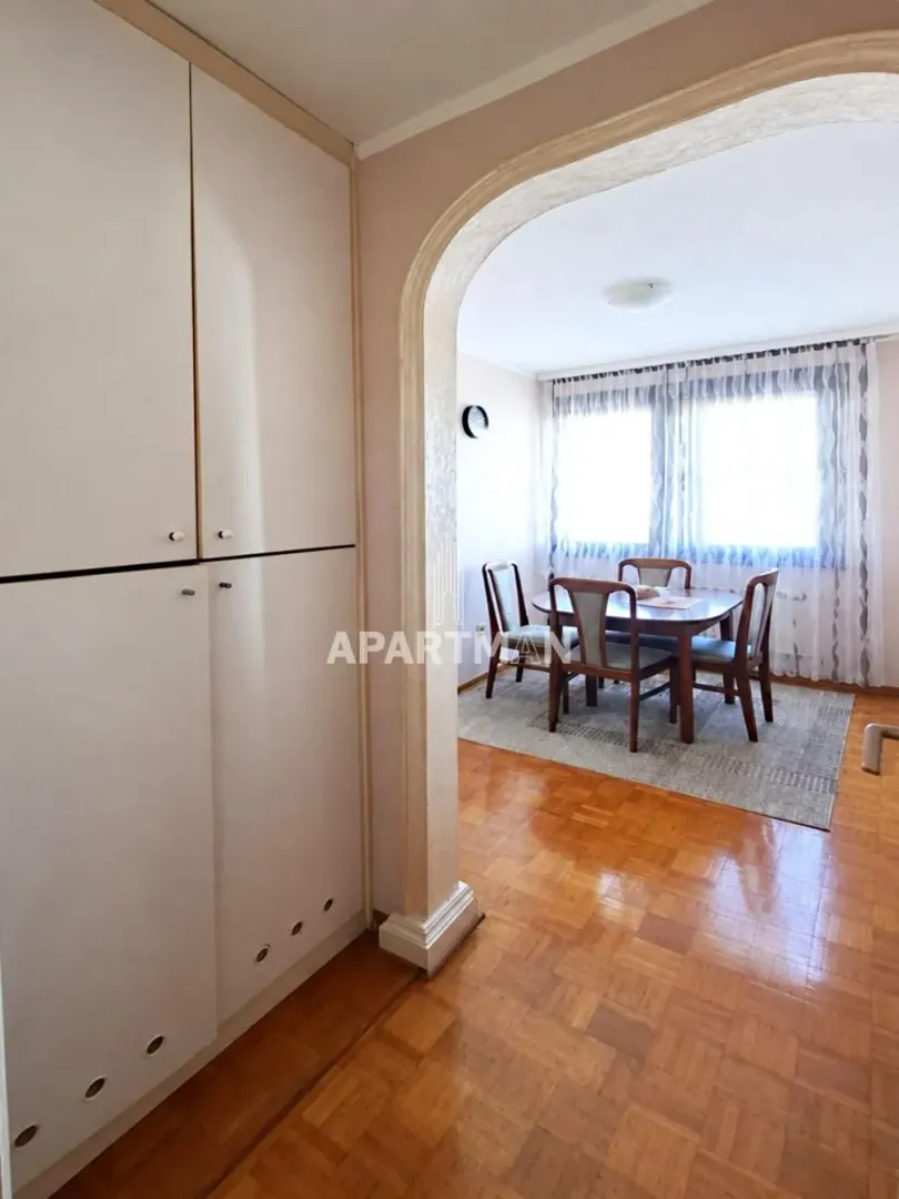 Pogled iz hodnika na trpezariju sa stolom i stolicama kroz dekorativni luk.
