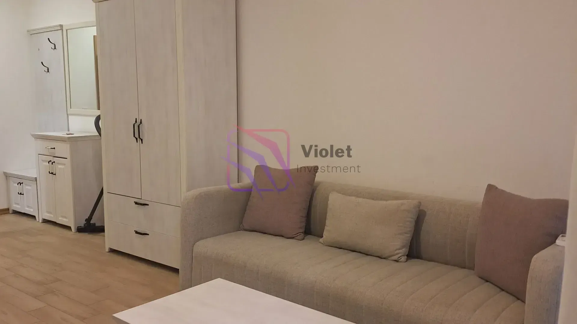 Dnevni boravak sa bež trosjedom, bijelim garderoberom i stočićem.