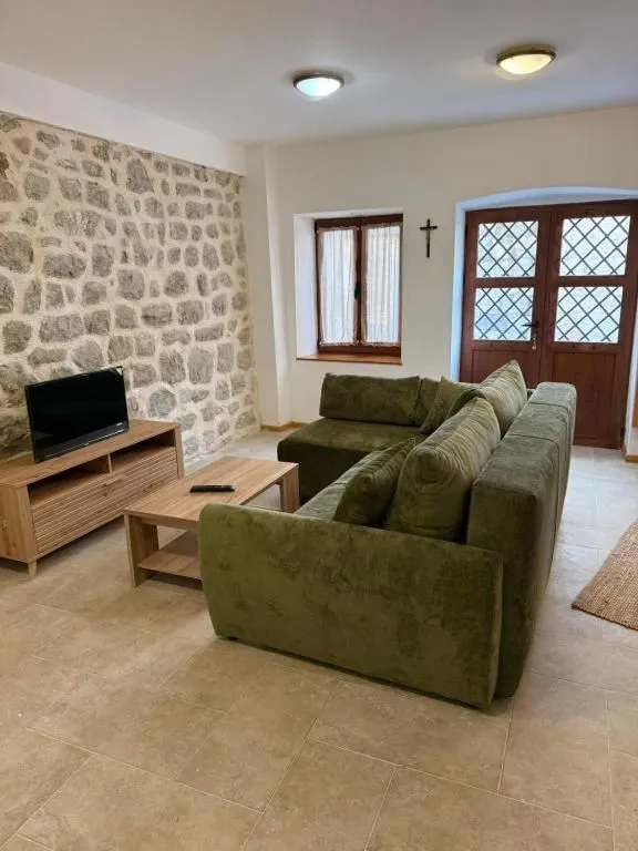 Living room with a green corner sofa and a stone wall.