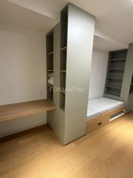 Small bedroom with a bed, built-in shelving units, and a desk. - image 8