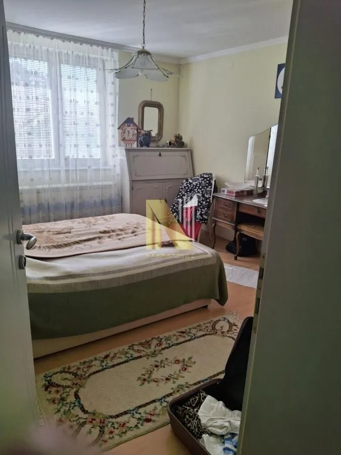 Pogled iz hodnika na nameštenu spavaću sobu sa krevetom i komodom.