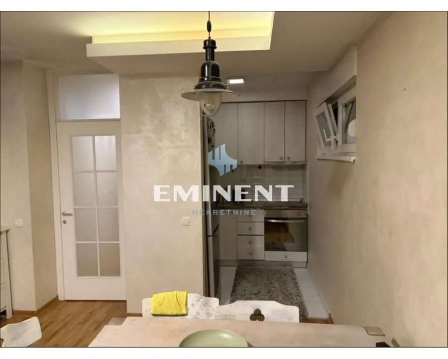 Small kitchen with white units and a built-in oven connected to the dining area.