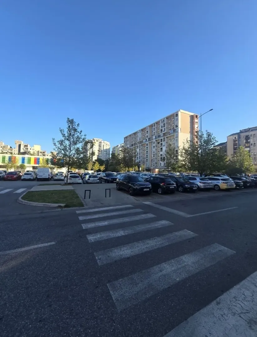 Pogled na stambene zgrade i parking ispred naselja.