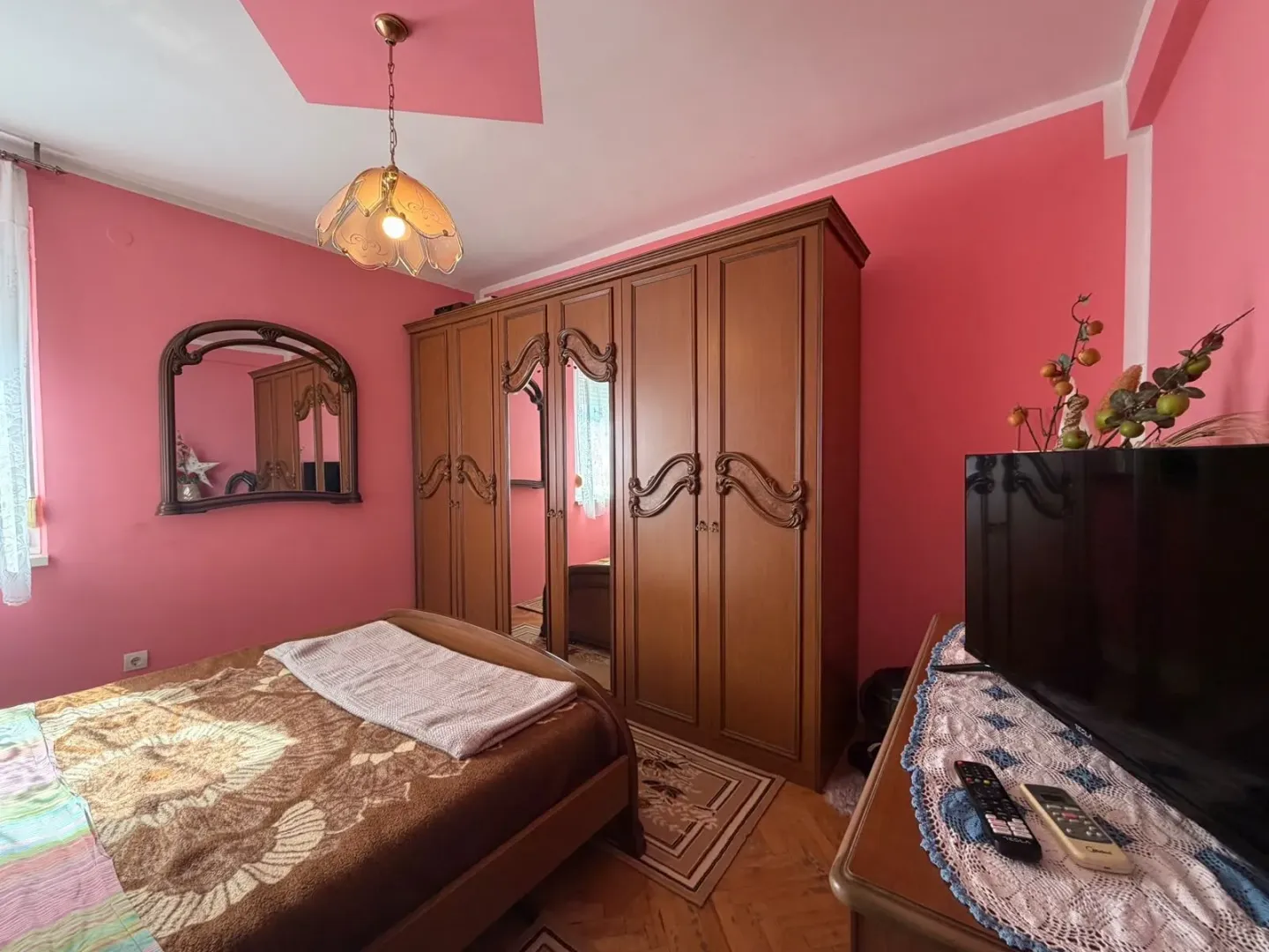 Bedroom with a double bed, wooden wardrobe and television.