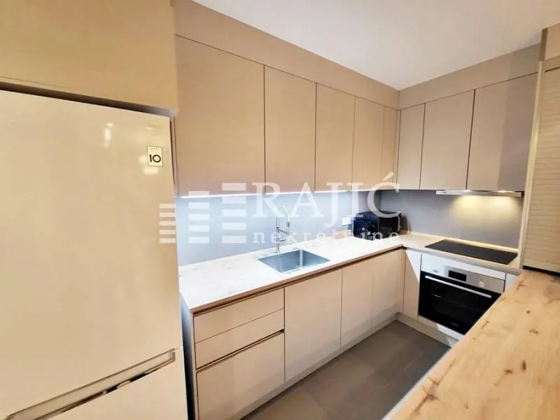 Modern kitchen with beige cabinets and built-in appliances.