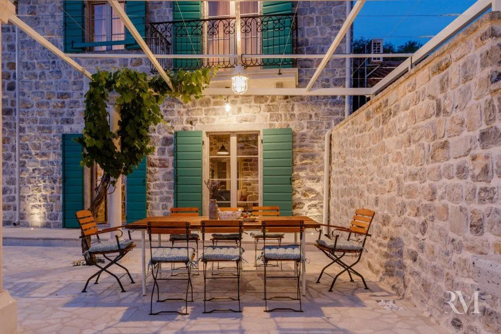 Courtyard of the house with stone walls and a dining table under a canopy.