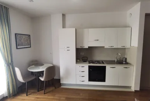 Modern kitchen with white cabinetry and a dining table with chairs. - image 7