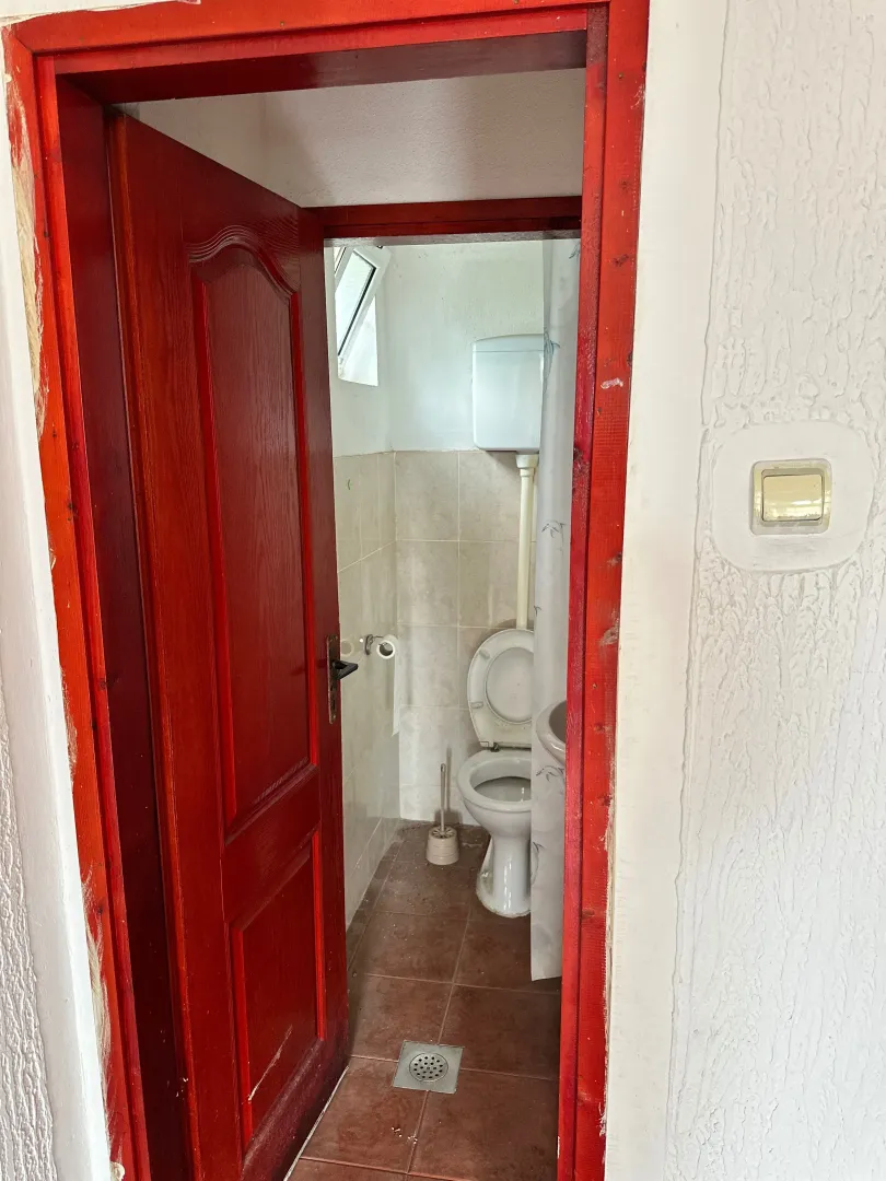 View of the bathroom through an open red wooden door frame.