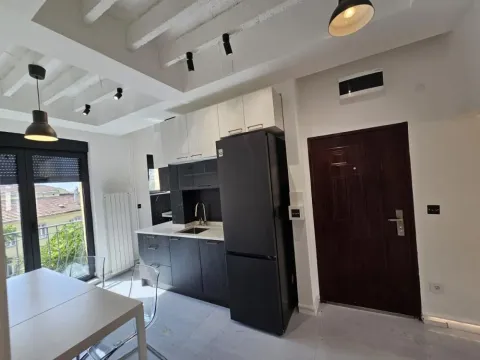 Modern kitchen with dark cabinetry and a dining table. - image 9