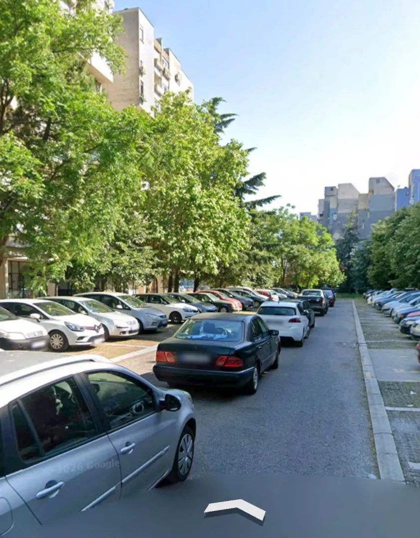 View of the parking lot in front of the residential building with trees.