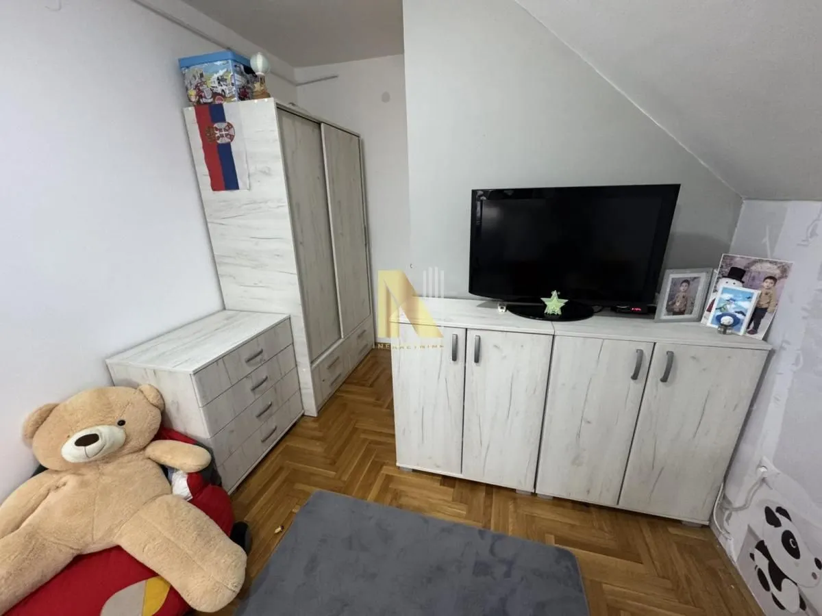Dečja soba sa krevetom, ormarom i televizorom.