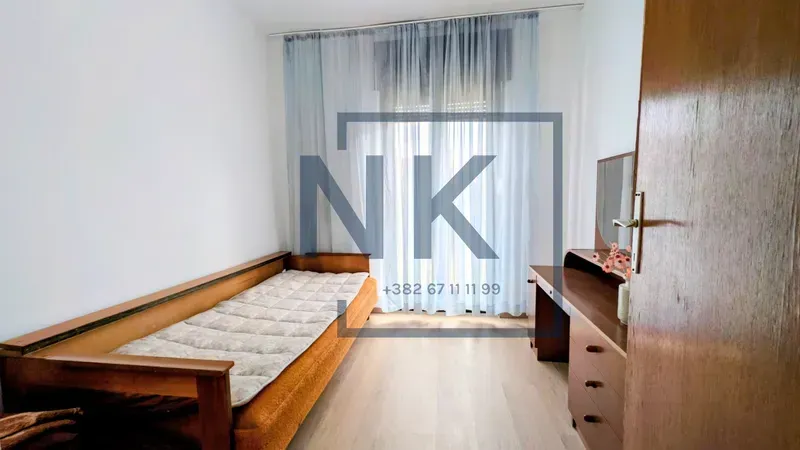 Small bedroom with a bed and wooden furniture.