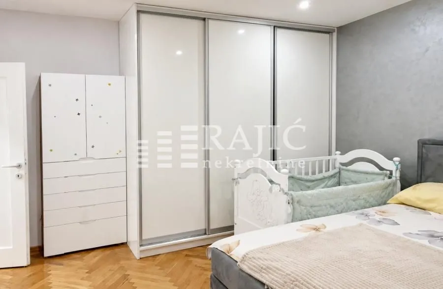 Children's bedroom with a crib, wardrobe, and double bed.