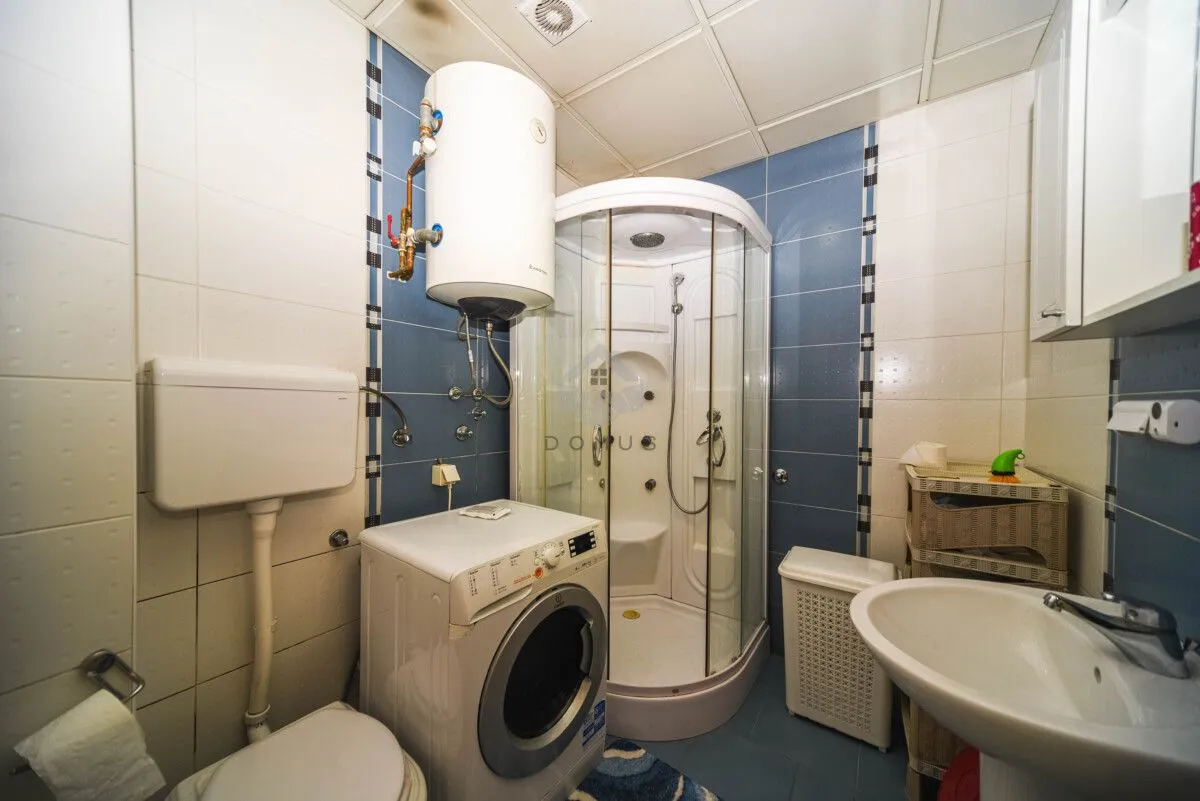 Bathroom equipped with a shower cabin, washbasin, toilet, washing machine, and water heater.