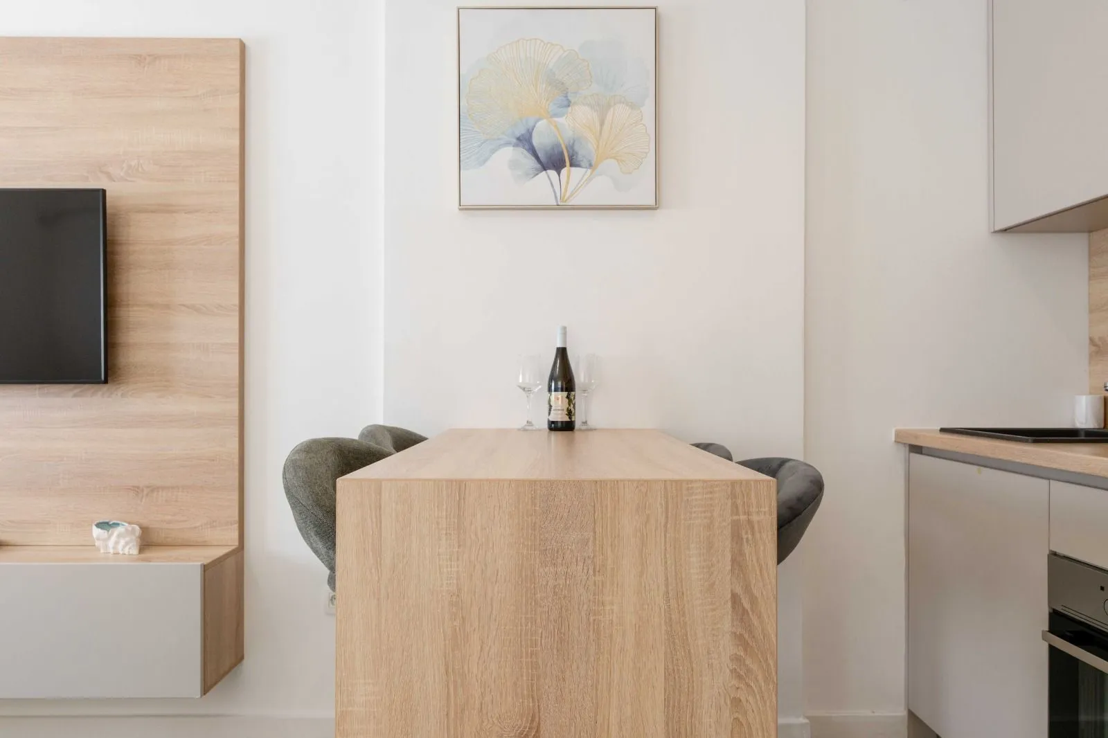 Wooden dining table with chairs and a bottle of wine in the kitchen area.