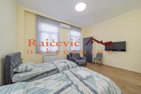 Spavaća soba sa dva singl kreveta, foteljom i televizorom na zidu. - image 5
