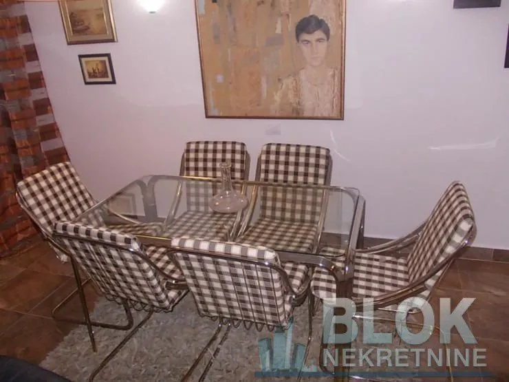 Dining area with a glass table and checkered chairs.