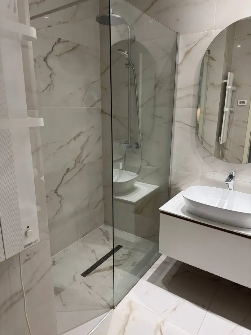 Modern bathroom with a shower cabin and a white sink.