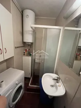 Small bathroom with a shower cabin, washbasin, and washing machine. - image 6