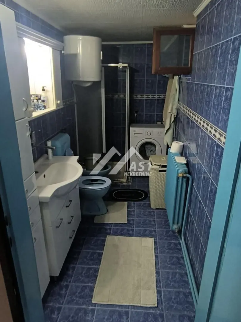 Tiled bathroom featuring a shower cabin, washbasin, and washing machine.