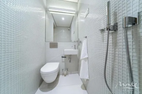Manje kupatilo obloženo bijelim mozaik pločicama sa tuš kabinom i umivaonikom. - image 31