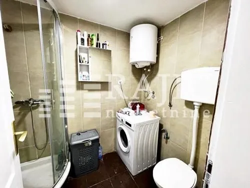 Smaller bathroom with a shower cabin, toilet, and washing machine.