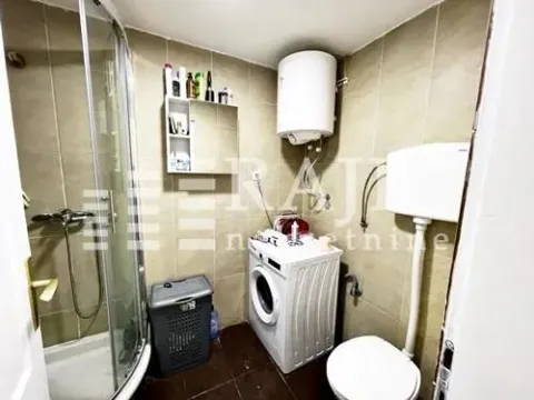 Smaller bathroom with a shower cabin, toilet, and washing machine. - image 12
