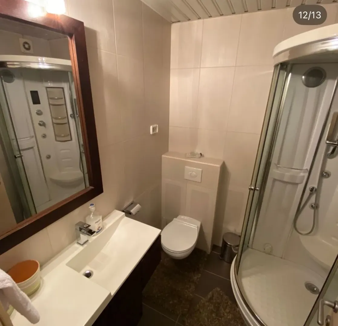 Compactly equipped bathroom with a shower cabin, washbasin, and toilet.