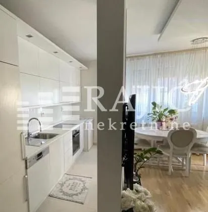 Modern white kitchen with built-in appliances and a view of the dining area.