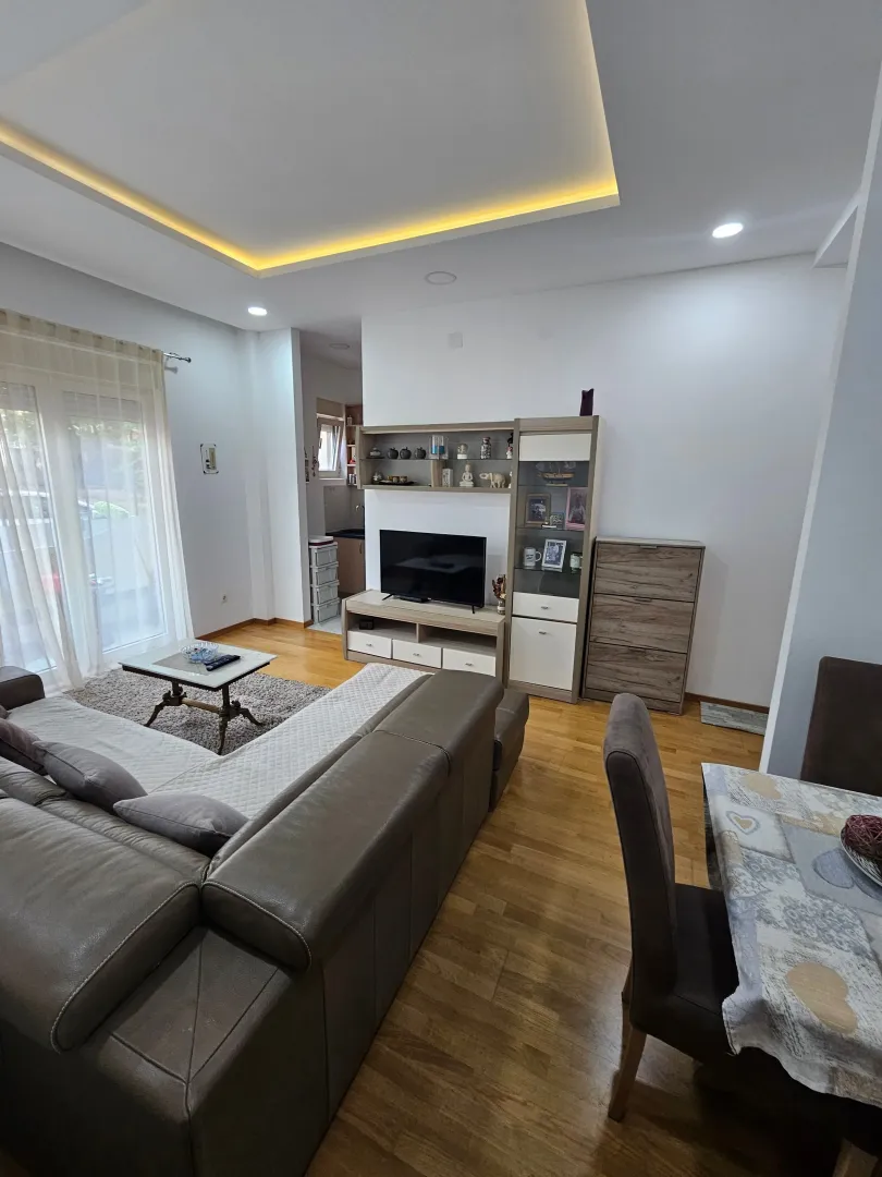 Living room with a sofa, TV unit, and dining table.