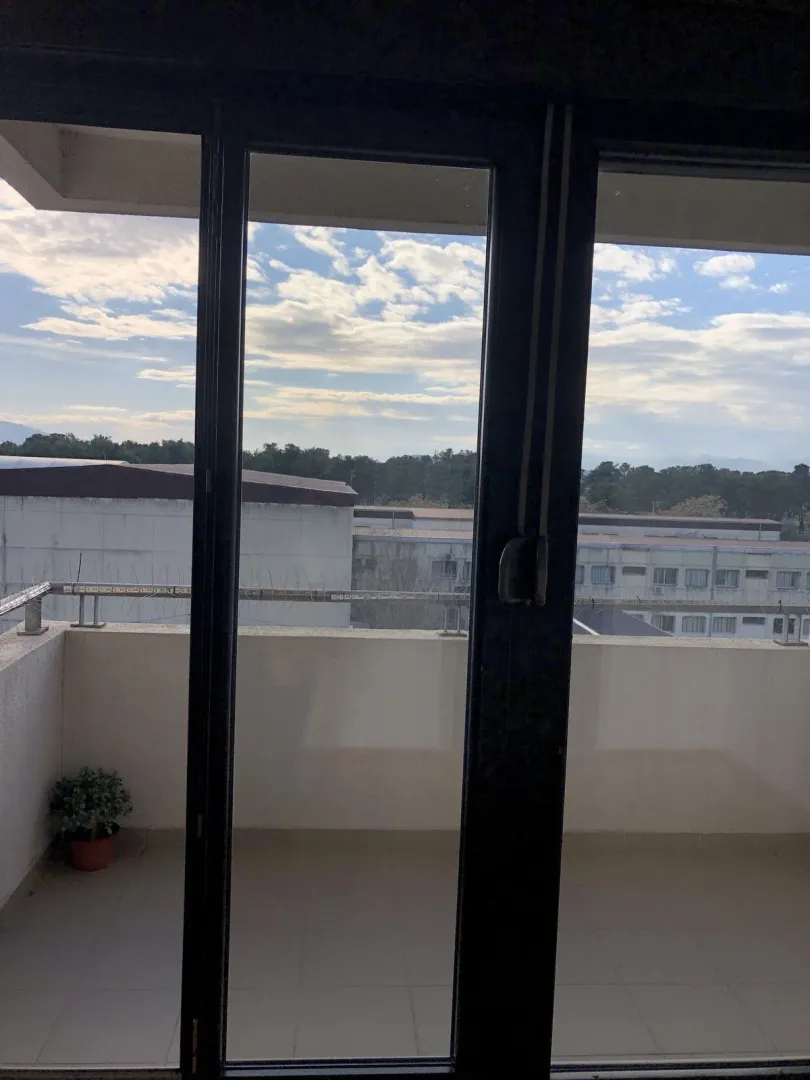 View of the balcony terrace and surroundings through a glass door.