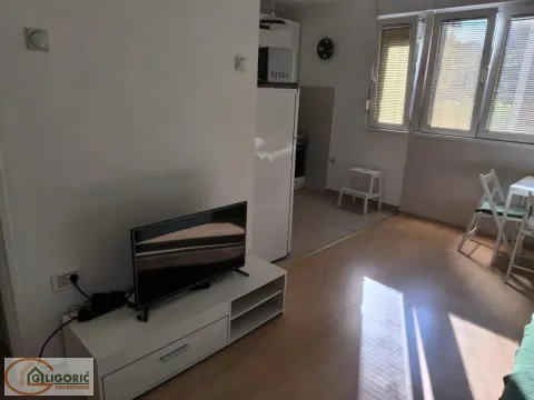 Living room with a TV and a view of the kitchen in the background. - image 2